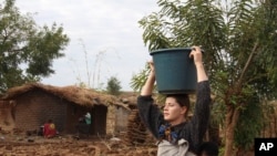 FILE - Cameron Beach, carries a carries a bucket of water on her head collected from a communal borehole in Dedza, near Lilongwe, Malawi, on July 23, 2021. The Peace Corps says it'll start sending volunteers overseas again in mid-March.