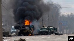 A Russian armored personnel carrier burns amid damaged and abandoned light utility vehicles after fighting in Kharkiv, Ukraine, Feb. 27, 2022. 