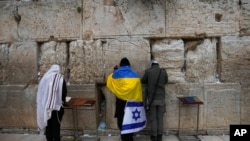 An ultra-Orthodox Jewish man wrapped in Ukrainian and Israeli national flags prays at the Western Wall, the holiest site where Jews can pray in Jerusalem's Old City, March 4, 2022.