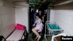 2022年3月2日，在俄罗斯入侵乌克兰期间，乌克兰基辅响起空袭警报声，护士帮助一名患者在围产中心的地下室避难。（路透社）
