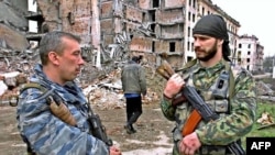 FILE - Russian special police unit officers talk to each other in downtown Grozny, Chechnya, as a Chechen man passes, March 2001.