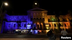 People look on as Cape Town's city hall is illuminated in the colors of the Ukrainian flag in support of Ukraine following its invasion by Russia, in Cape Town, South Africa, March 2, 2022.