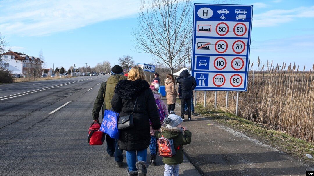 Familias ucranianas huyen del conflicto en su país caminando con sus pertenencias por una carretera cerca del cruce fronterizo húngaro-ucraniano cerca de Beregsurany, Hungría, a unos 300 km de la capital húngara.