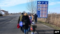 Familias ucranianas huyen del conflicto en su país caminando con sus pertenencias por una carretera cerca del cruce fronterizo húngaro-ucraniano cerca de Beregsurany, Hungría, a unos 300 km de la capital húngara.