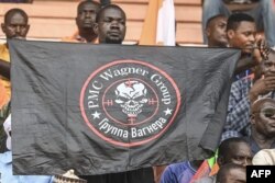 FILE - A man holds a flag bearing the logo of Private Military Company (PMC) Wagner as supporters of Niger's National Council for Safeguard of the Homeland (CNSP) gather at the General Seyni Kountche stadium in Niamey on Agust 26, 2023.