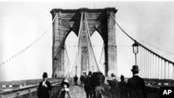 Pedestrians stroll along the promenade of the Brooklyn Bridge, connecting Manhattan and Brooklyn, New York City, 1891.