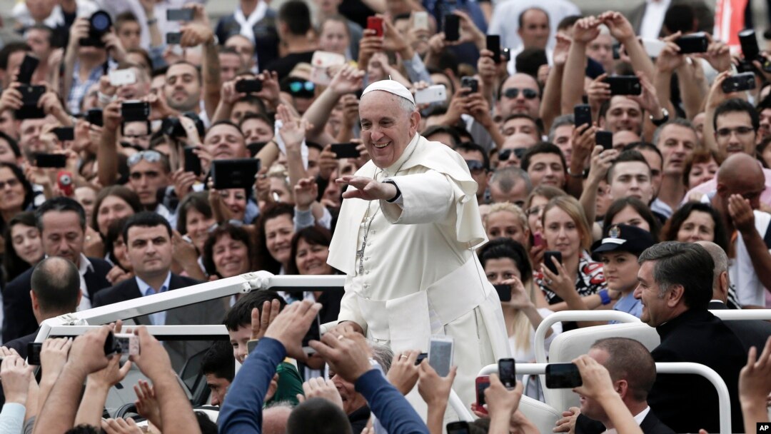 Pope Francis waves to faithful as he is driven through the crowd in Mother Teresa Square in Tirana, Sept. 21, 2014. 