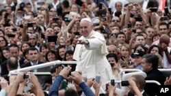 Pope Francis waves to faithful as he is driven through the crowd in Mother Teresa Square in Tirana, Sept. 21, 2014. 