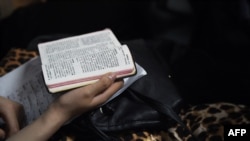 FILE - A woman holding a bible during a Christmas Eve service held by members of an underground church, at an apartment in Beijing, Dec. 24, 2014.