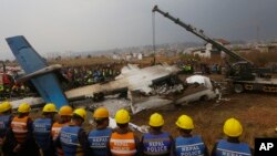 FILE- In this Monday, March 12, 2018 file photo, Nepalese rescuers and police are seen near the debris after a passenger plane from Bangladesh crashed at the airport in Kathmandu.