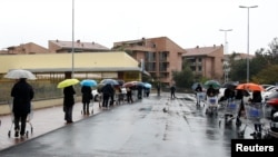 FILE - People line up in the rain outside a supermarket after the Italian island of Sicily closed them, as it tightens measures to try and contain the spread of coronavirus disease, in Catania, Italy, March 23, 2020.