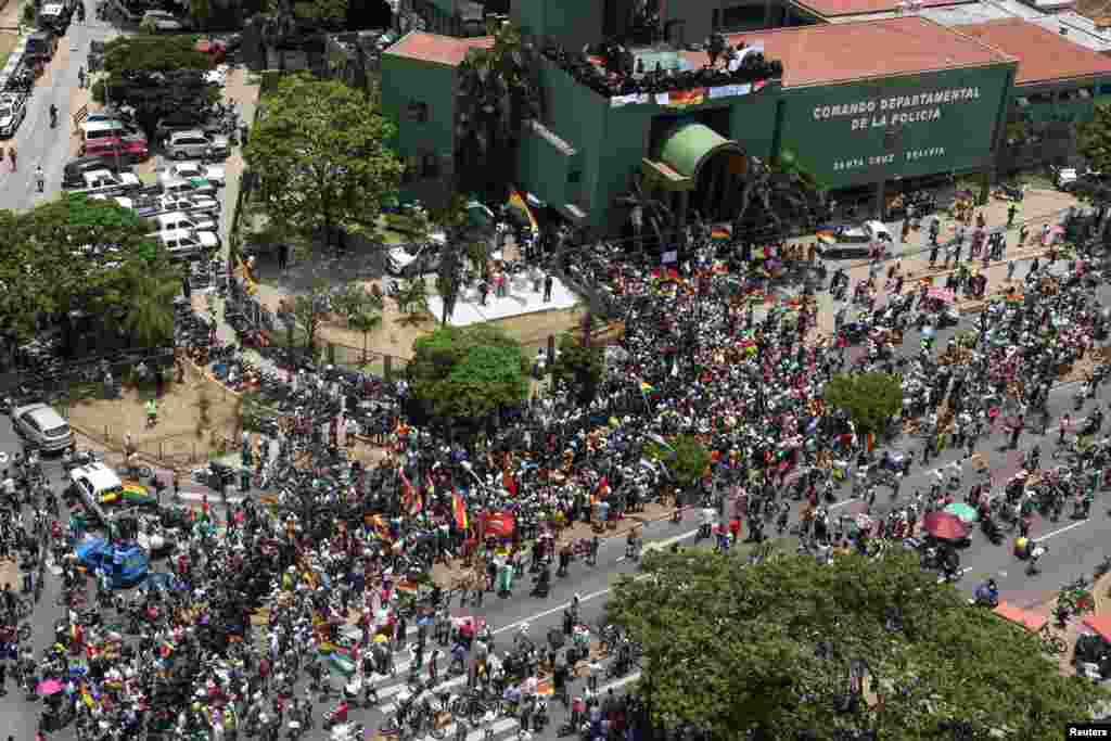 Las personas se reúnen fuera de la sede de la policía, mientras los agentes de policía se paran en una terraza del edificio.