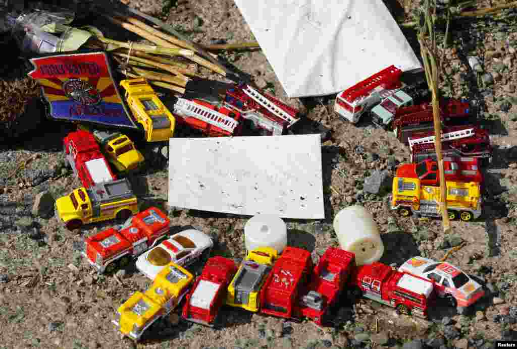 A circle of toy fire trucks sit at the bottom of a memorial dedicated to the 19 firefighters killed in the nearby wildfire in Prescott, Arizona, July 8, 2013. 