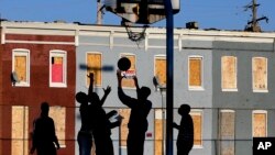 Jóvenes juegan frente a un vecindario de casas abandonadas en Baltimore. La pobreza en Estados Unidos es peor de lo pensado.