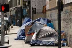 FILE - Tents and tarps erected by homeless people are shown along sidewalks and streets in the skid row area of downtown Los Angeles, California,  June 28, 2019.