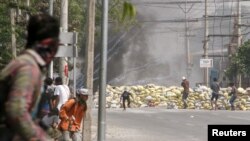 Waandamanaji wakijificha wakati wa maandamano ya kupinga mapinduzi ya kijeshi mjini Mandalay, Myanmar Machi 15, 2021. REUTERS/Stringer