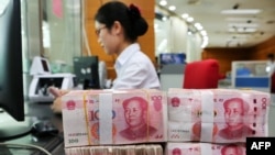 Nhân viên ngân hàng đang kiểm tra đồng 100 tệ tại một ngân hàng ở Nam Thông, Trung Quốc.