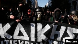Masked youths take part in an anniversary rally marking the shooting of a 15-year-old student by a policeman in 2008, in Athens, Dec. 6, 2014. 