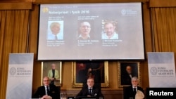 Les membres de l'Académie royale des sciences Nils Martensson, Goran K Hansson et Thomas Hans Hansson, sont assis sous la photographie des prix Nobel David Thouless, Duncan Haldane and Michael Kosterlitz, à Stockholm, Suède, le 4 octobre 2016.