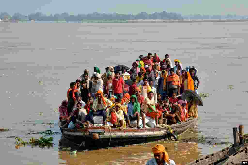 Flood-affected people, along with their belongings, move to a safer place in a boat after the rise in the water level of river Ganges following heavy rains, in Patna, India.