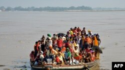 Flood-affected people move to a safer place in a boat after the rise in the water level of river Ganges following heavy rains, in Patna, India.