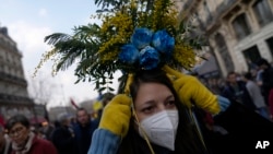 A woman wears flowers with colors of the Ukrainian flag during a demonstration march against the Russian invasion of Ukraine, in Paris, March 5, 2022.