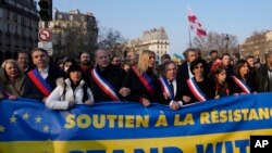 Paris Mayor and socialist presidential candidate Anne Hidalgo, right, walks with politicians holding a banner reading "Stand With Ukraine" during a march against the Russian invasion of Ukraine, in Paris, March 5, 2022.