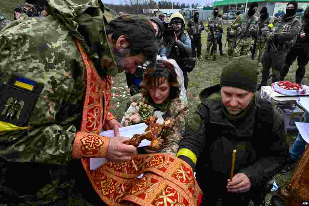 Servicemen of Ukrainian territorial defense, Valery (R) and Lesya (C), get married not far from check-point on Kyiv outskirts, March 6, 2022.