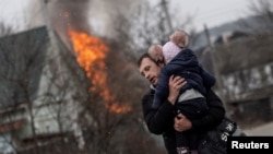 A man and a child escape from the town of Irpin, after heavy shelling on the only escape route used by locals, while Russian troops advance towards the capital of Kyiv, in Irpin, near Kyiv, Ukraine March 6, 2022. REUTERS/Carlos Barria