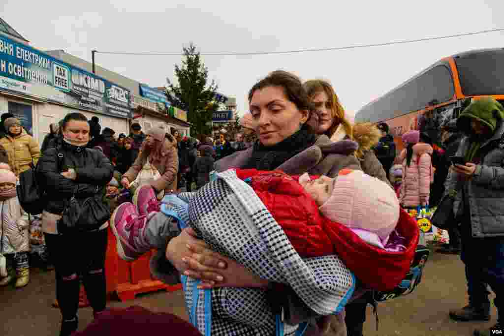 A woman waits with her baby to cross Ukraine and Poland border in Shehyni, Ukraine, March 4, 2022. Thousands of people have crossed the border on foot since the beginning of the war.&nbsp; (VOA/Yan Boechat)