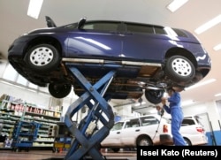 Seorang pekerja sedang melakukan pengecekan sebuah mobil di toko dealer mobil di Tokyo 1 November 2010. (Foto: Reuters/Issei Kato)