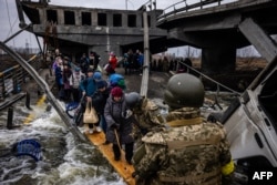 7일 우크라이나 수도 크이우(러시아명 키예프) 북서부 도시 이르핀 주민들이 파괴된 교량 아래 임시 가설물 위에서 이동하고 있다.