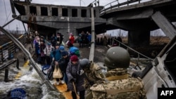 Evacuees cross a destroyed bridge as they flee the city of Irpin, northwest of Kyiv, March 7, 2022. Ukraine dismissed Moscow's offer to set up humanitarian corridors after it emerged some routes would lead refugees into Russia or Belarus.