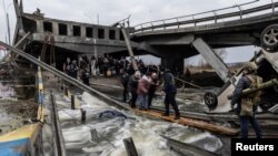 Los residentes locales cruzan un puente destruido mientras salen de la ciudad de Irpin, cerca de Kiev, la capital, después de días de intensos bombardeos en Ucrania por parte de fuerzas rusas, el 7 de marzo de 2022. 