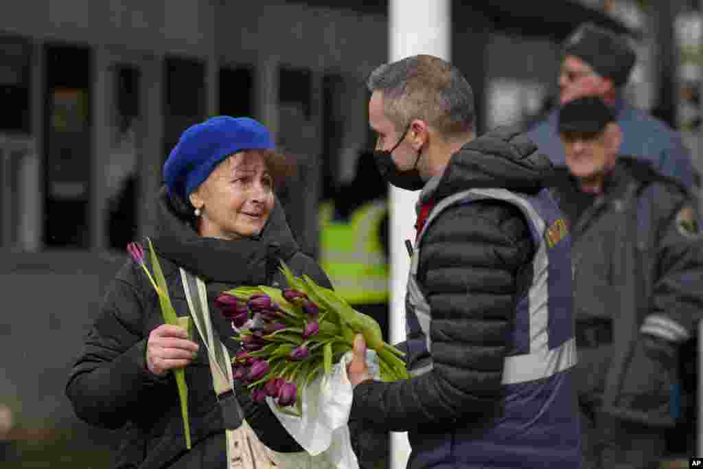 A Romanian Immigrations officer gives flowers to a refugee fleeing the conflict from neighboring Ukraine after she crossed the border on International Women&#39;s Day, at the Romanian-Ukrainian border, in Siret, Romania, March 8, 2022.