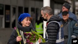 Seorang petugas Imigrasi Rumania memberikan bunga kepada seorang pengungsi dari negara tetangga Ukraina yang melarikan diri dari konflik saat melintasi perbatasan Rumania-Ukraina, di Siret, Rumania, pada Hari Perempuan Internasional, Selasa, 8 Maret 2022. (AP/Andreea Alexandru)