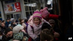 Orang-orang berjuang untuk naik kereta api ke Lviv di stasiun Kyiv, Ukraina, sambil menggendong anak-anak mereka, Senin, 7 Maret 2022. Rusia membuka beberapa koridor kemanusiaan untuk memungkinkan warga sipil melarikan diri dari Ukraina. (Foto AP/Emilio Morenatti)