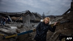 Una mujer descansa después de cruzar un puente destruido mientras sale de la ciudad de Irpin, al noroeste de Kiev, el 7 de marzo de 2022.