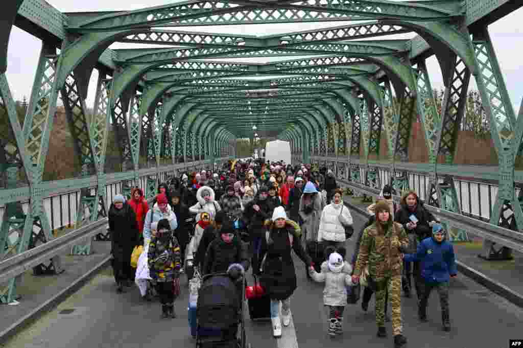 Ukrainian refugees walk a bridge&nbsp;in the border crossing of Zosin-Ustyluh, western Ukraine, at the border with Poland, March 6, 2022.