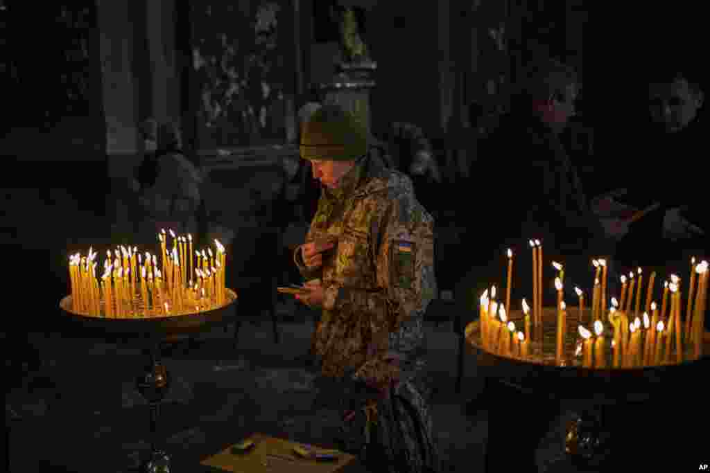 A Ukrainian woman dressed in military attire prays inside the Saints Peter and Paul Garrison Church in Lviv, western Ukraine, March 6, 2022.