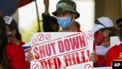 People hold signs in front of the Hawaii state Capitol during a rally calling for the closure of the Navy's Red Hill underground fuel storage facility near Pearl Harbor, in Honolulu, Feb. 11, 2022. 