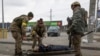 Militares ucranianos tentam ajudar um homem ferido, cidade de Irpin, Ucrânia, 6 de Março, 2022. 