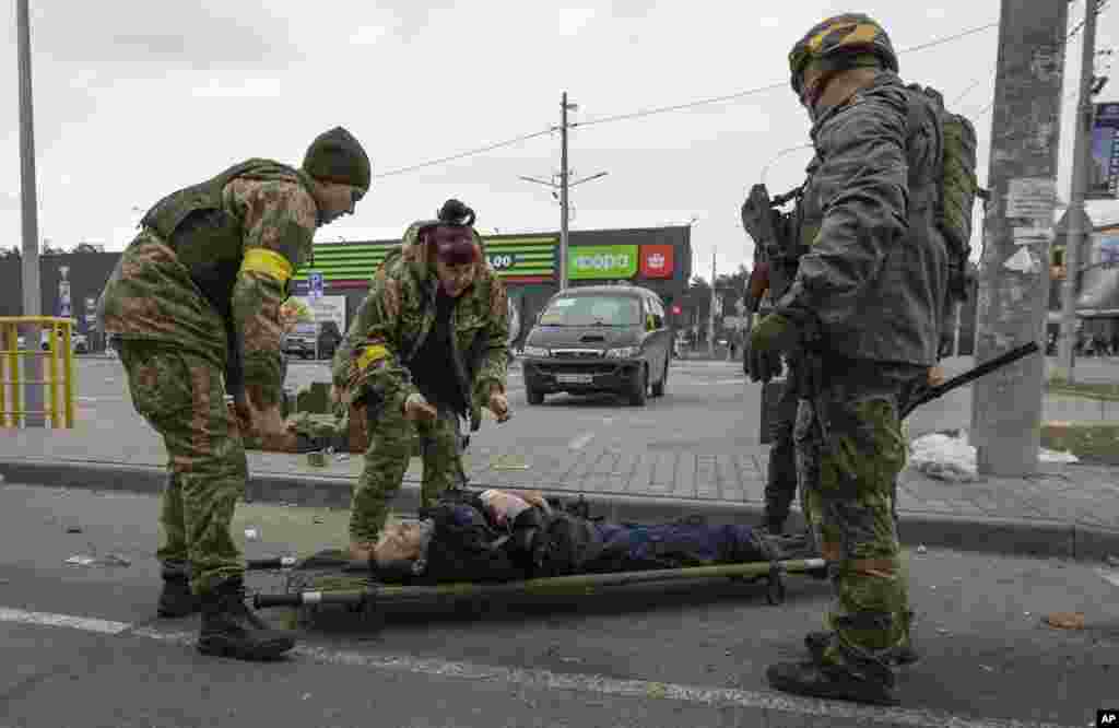 Ukrainian servicemen try to help a wounded man, in the town of Irpin, March 6, 2022.