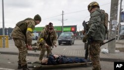 Украинские военные оказывают помощь раненому. 6 марта 2022 г. 