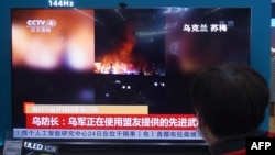 Seorang warga menyaksikan televisi yang menayangkan berita tentang konflik antara Rusia dan Ukraina di salah satu pusat perbelanjaan di Hangzhou, Provinsi Zhejiang, China, pada 25 Februari 2022. (Foto: AFP)