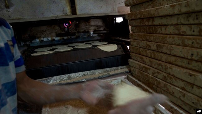 A baker prepares Egyptian traditional 'baladi' flatbread, at a bakery, in el-Sharabia, Shubra district, Cairo, Egypt, Wednesday, March 2, 2022. (AP Photo/Nariman El-Mofty)
