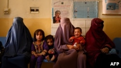 FILE - Women wait with their children at a maternity clinic in a rural area of Dand district in Kandahar province of Afghanistan, Oct. 1, 2020.