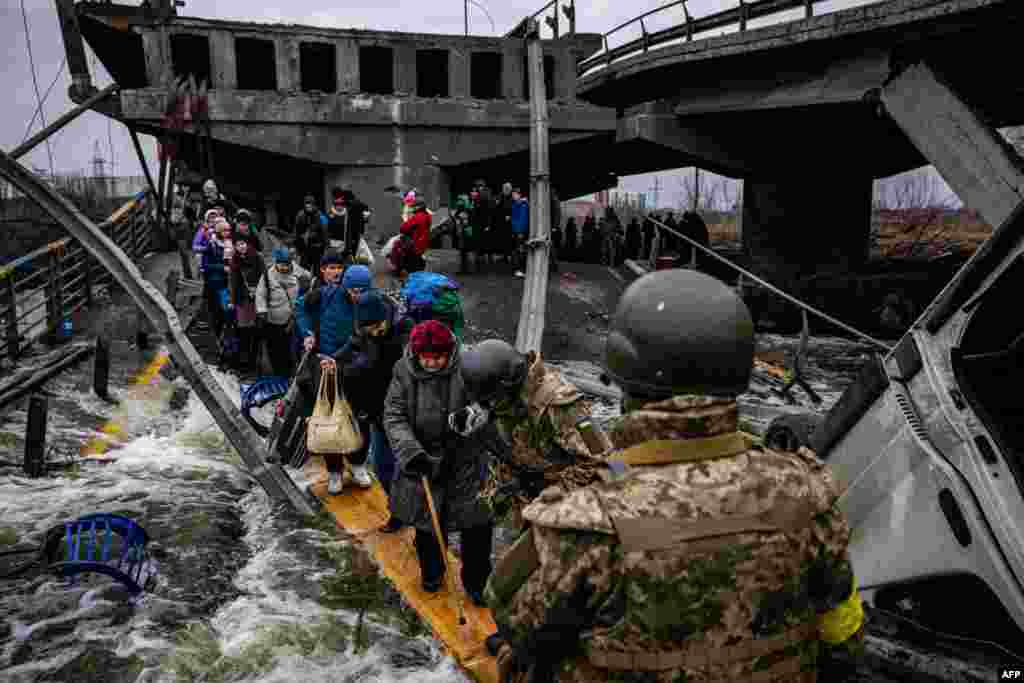 Evacuees cross a destroyed bridge as they flee the city of Irpin, northwest of Kyiv, March 7, 2022. Ukraine dismissed Moscow&#39;s offer to set up humanitarian corridors from several bombarded cities after it emerged some routes would lead refugees into Russia or Belarus.