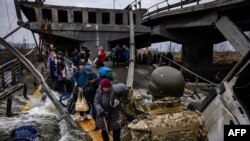 ဗုံးဒဏ်ကြောင့် ပျက်စီးသွားတဲ့ တံတားကို ဖြတ်လာနေတဲ့ ယူကရိန်းနိုင်ငံ မြို့တော် Kyiv အရှေ့မြောက်မှာရှိတဲ့ Irpin မြို့ကထွက်ပြေးလာတဲ့ စစ်ပြေးဒုက္ခသည်များ (မတ်လ ၇၊ ၂၀၂၂)
