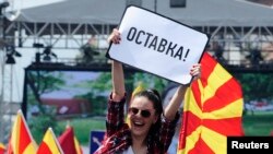 Seorang perempuan mengibarkan poster bertuliskan "mengundurkan diri" dalam demo anti pemerintah di Skopje, Macedonia, 17 Mei 2015. 